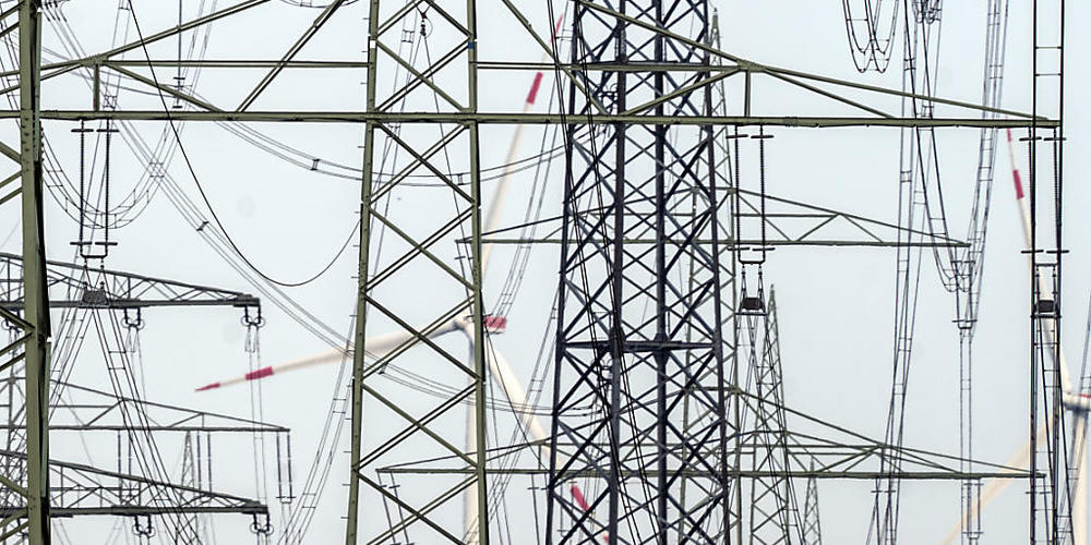 ARCHIV - Hinter einem Wald aus Strommasten drehen sich Windräder, die Strom erzeugen. Foto: Federico Gambarini/dpa