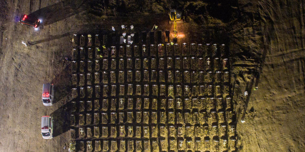 dpatopbilder - In Jakarta stehen Mitarbeiter (oben) in weißer Schutzkleidung um Gräber herum, während neben ihnen ein Bagger weitere Gräber aushebt. In Indonesien sind mehr als 69 000 Menschen in Verbindung mit Covid-19 gestorben. Foto: Wisnu Pras...