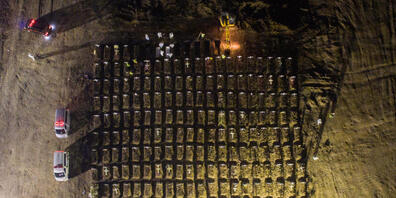 dpatopbilder - In Jakarta stehen Mitarbeiter (oben) in weißer Schutzkleidung um Gräber herum, während neben ihnen ein Bagger weitere Gräber aushebt. In Indonesien sind mehr als 69 000 Menschen in Verbindung mit Covid-19 gestorben. Foto: Wisnu Pras...