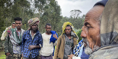 Männer versammeln sich, um mit dem am Arm verletzten Milizionär Kibret Bidere (2.v.r) in der Nähe des Dorfes in der Amhara-Region in Nordäthiopien zu sprechen. Foto: Uncredited/AP/dpa