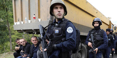 Kosovo-Polizisten patrouillieren an Lastwagen vorbei, wo Kosovo-Serben eine Straße in der Nähe des nördlichen Kosovo-Grenzübergangs Jarinje blockieren. Foto: Bojan Slavkovic/AP/dpa