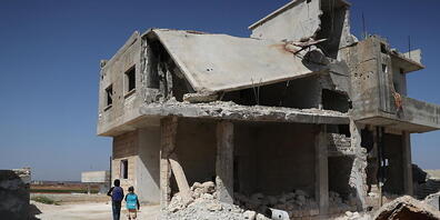 Kinder laufen an einem zerstörten Haus in Idlib vorbei, nachdem sie ihre Schule zu Beginn des Schuljahres verlassen haben. Foto: Anas Alkharboutli/dpa