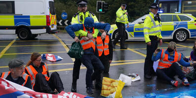 Polizisten nehmen Aktivisten der Organisation «Insulate Britain» auf einer Londoner Autobahn fest. Foto: Steve Parsons/PA Wire/dpa