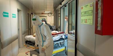 ARCHIV - Medizinische Mitarbeiter in Schutzkleidung schieben das Bett eines Corona-Patienten im städtischen Krankenhaus Nr. 52 in Moskau. (Archivbild) Foto: Denis Grishkin/Moscow News Agency/AP/dpa