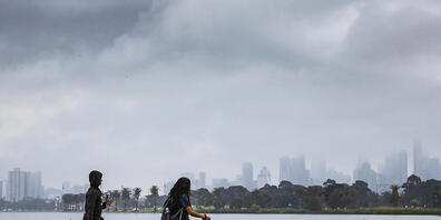 People are seen walking a dog at Albert Park Lake in Melbourne, Thursday, September 30, 2021. Melbourne's lockdown will remain in place until 70 per cent of Victorians aged over 16 are double-vaccinated, which is forecast for October 26. (AAP Imag...