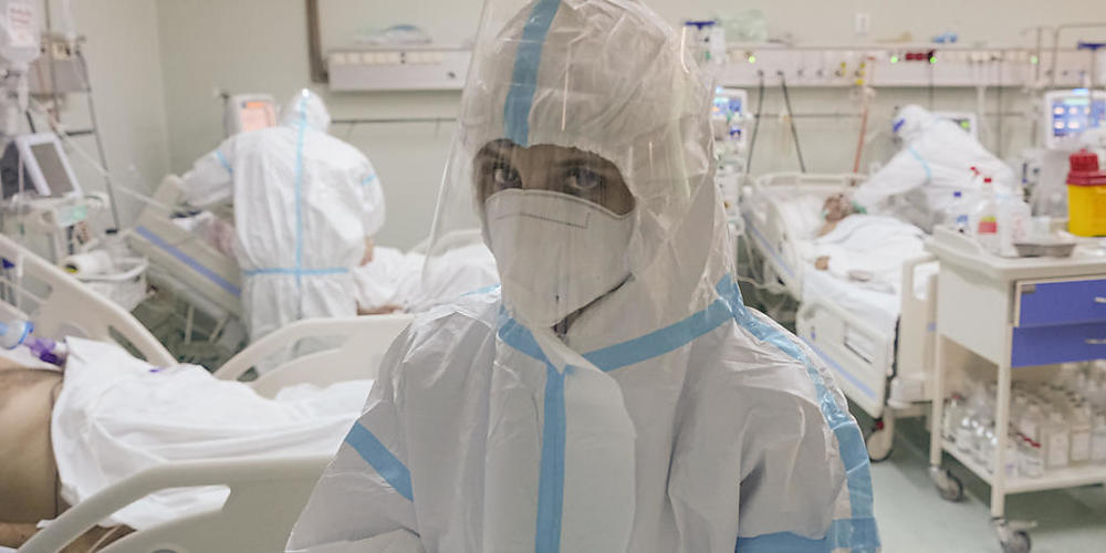Eine medizinische Mitarbeiterin richtet ihre Handschuhe auf der Corona-Intensivstation. Foto: Vadim Ghirda/AP/dpa