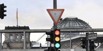 ARCHIV - Eine Ampel, an der die Farben Rot, Gelb und Grün gleichzeitig leuchten, ist vor der Kuppel des Reichstagsgebäudes zu sehen. SPD, Grüne und FDP wollen über eine mögliche Ampelkoalition verhandeln. Foto: Julian Stratenschulte/dpa