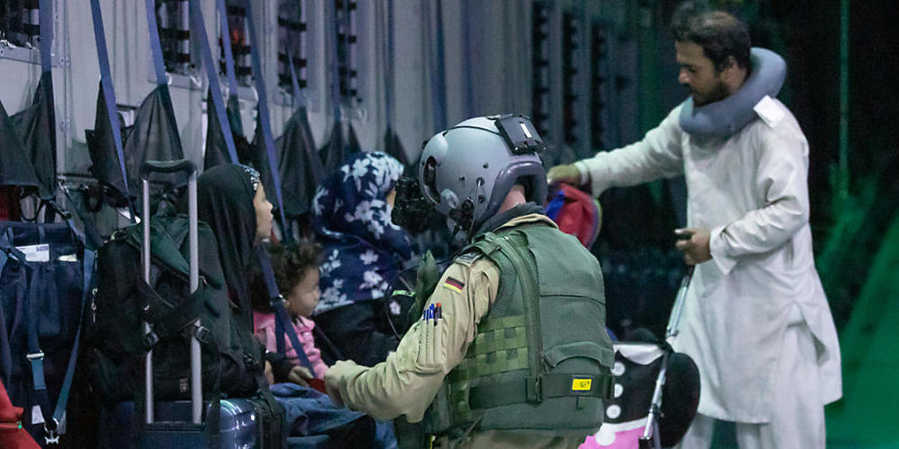 HANDOUT - Ein Ladungsmeister der Bundeswehr hilft Afghanen beim Anschnallen im Transportflugzeug A400M am Flughafen von Kabul. Wegen chaotischer Verhältnisse am Flughafen ist die Evakuierung aus der afghanischen Hauptstadt durch die Bundeswehr ins...
