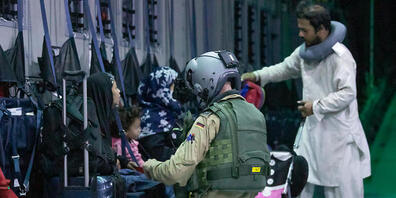 HANDOUT - Ein Ladungsmeister der Bundeswehr hilft Afghanen beim Anschnallen im Transportflugzeug A400M am Flughafen von Kabul. Wegen chaotischer Verhältnisse am Flughafen ist die Evakuierung aus der afghanischen Hauptstadt durch die Bundeswehr ins...