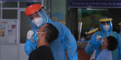Mitarbeiter im Gesundheitswesen entnehmen zwei Männern einen Abstrich. Vietnam hat am Sonntag nach Angaben des Gesundheitsministeriums 737 Tote im Zusammenhang mit dem Coronavirus registriert - so viele Tote binnen eines Tages hat es in dem Land n...