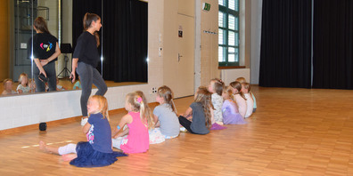 Aufmerksame Kinderaugen: Yara Auf der Mauer erklärt der Kindergruppe, was sie in der kommenden Tanzstunde machen werden.
