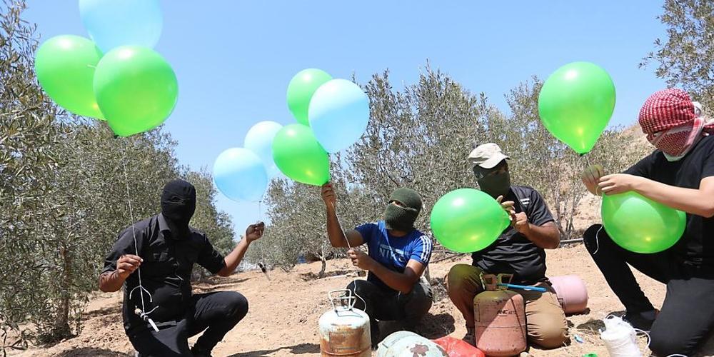 Maskierte Palästinenser bereiten in der Nähe des Lagers Al-Bureij im Zentrum des Gazastreifens Brandballons vor (24.08.2021). Nach Angriffen militanter Palästinenser im Gazastreifen mit Brandballons hat Israels Luftwaffe erneut Ziele in dem Paläst...
