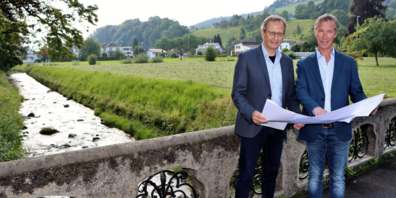 Der Rheinecker Stadtpräsident Urs Müller (links) und der Thaler Gemeindepräsident Felix Wüst (rechts) setzen sich für eine möglichst rasche Erhöhung der Hochwassersicherheit am Freibach ein. Auf der Wiese im Hintergrund soll ein Geschiebesammler entstehen