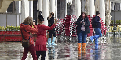 Menschen auf dem überfluteten Markusplatz. Wegen Unwettern und starker Winde droht der norditalienischen Lagunenstadt Hochwasser. Foto: Matteo Tagliapietra/LaPresse/dpa
