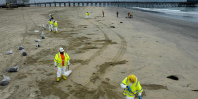 Arbeiter in Schutzanzügen säubern einen vom ausgetretenen Öl verunreinigten Strand in Newport Beach in Kalifornien. Foto: Ringo H.W. Chiu/AP/dpa