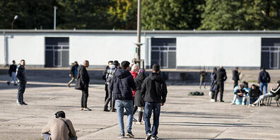 Asylsuchende laufen in der Erstaufnahmeeinrichtung Eisenhüttenstadt über einen Platz. Foto: Fabian Sommer/dpa