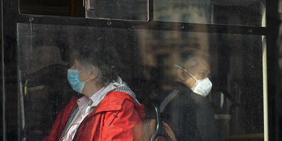 Menschen tragen Mund-Nasen-Schutz, während sie in einem Bus in London sitzen. Foto: Alberto Pezzali/AP/dpa