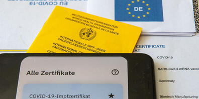 ARCHIV - Ein Impfpass und ein Smartphone, auf dem die App CovPass läuft, liegen auf einem Impfzertifikat, das von einer Apotheke ausgestellt wurde. Ohne Booster sind EU-Impfzertifikate künftig spätestens neun Monate nach der Grundimmunisierung ung...