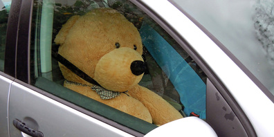 Der Teddybär in einem Auto in Lachen.