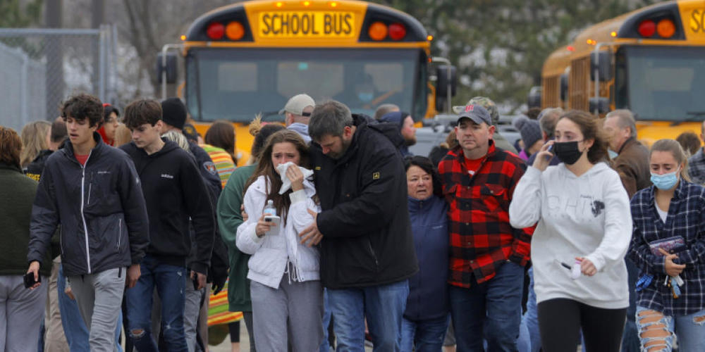 Eltern verlassen mit ihren Kindern einen Parkplatz, wo sich viele Schüler nach einer Schießerei an der Oxford High School im US-Bundesstaat Michigan versammelt haben. Foto: Eric Seals/Detroit Free Press via AP/dpa