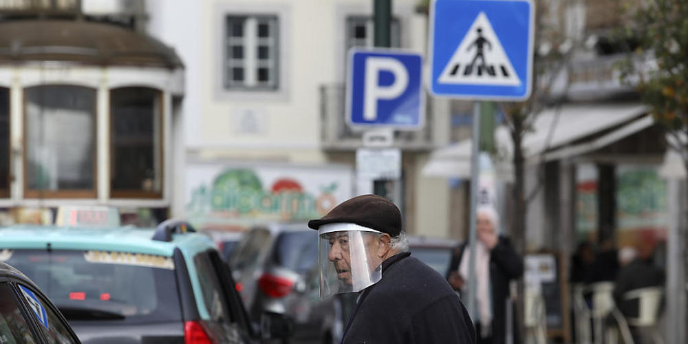 Ein alter Mann mit einem Gesichtsschutz überquert eine Straße. Auch in Portugal ist erstmals die neue Coronavirus-Variante Omikron festgestellt worden. Foto: Ana Brigida/AP/dpa