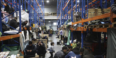 Diese Migranten sind in einem Logistikzentrum an der belarussisch-polnischen Grenze untergekommen. Die EU will Sanktionen gegen Migration über Belarus in Kraft setzen. Foto: Oksana Manchuk/BelTA/AP/dpa - ACHTUNG: Nur zur redaktionellen Verwendung ...