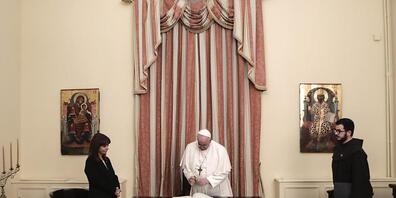 HANDOUT - Papst Franziskus (M) trägt sich in ein Gästebuch ein neben Katerina Sakellaropoulou (l), Präsidentin von Griechenland. Das Oberhaupt der katholischen Kirche lobte in seiner Rede die Errungenschaften der Politik und warnte zugleich vor de...