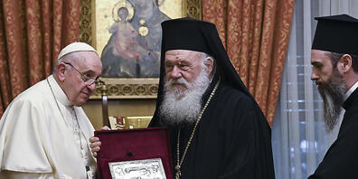 Papst Franziskus (l) tauscht Geschenke mit dem griechisch-orthodoxen Erzbischof Hieronymos II. (M) während eines Treffens im orthodoxen Erzbistum aus. Foto: Andreas Solaro/AFP POOL/AP/dpa