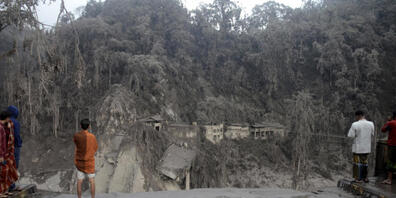 Dorfbewohner stehen vor einem Hang an der eine Brücke durch den Lavastrom, bei Ausbruch des Mount Semeru, zerstört wurde. Foto: Hendra Permana/AP/dpa