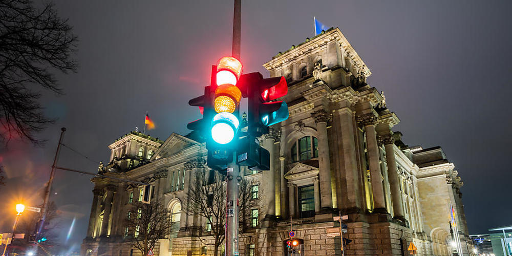 Eine Ampel leuchtet in einer Aufnahme mit Langzeitbelichtung am Morgen vor dem Reichstagsgebäude in allen drei Phasen. Foto: Christoph Soeder/dpa