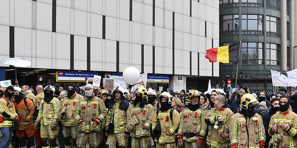 Demonstranten und Feuerwehrleute stehen bei einem Protest gegen die Corona-Maßnahmen auf einer Straße. In mehreren europäischen Städten sind am Wochenende wieder Gegner von staatlichen Einschränkungen zur Bekämpfung des Coronavirus auf die Straße ...