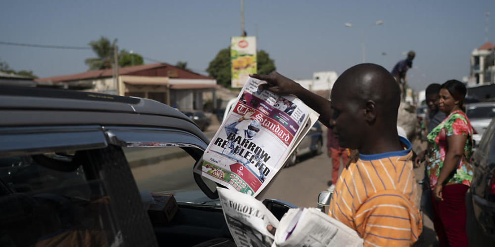 Ein Mann verkauft eine Zeitung, deren Titelseite die Wiederwahl des gambischen Präsidenten Barrow zeigt mit der Schlagzeile «Barrow re-elected». Foto: Leo Correa/AP/dpa