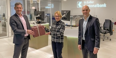 Thomas Lehmann, Leiter SGKB Gossau (links), und Stefano Tognazzi, Leiter Privatkunden SGKB Gossau (rechts), übergeben Monika Bischof-Wiesli, Stellenleitung Pro Senectute Gossau & St. Gallen Land, die Weihnachtsspende in Form eines Geschenkes.