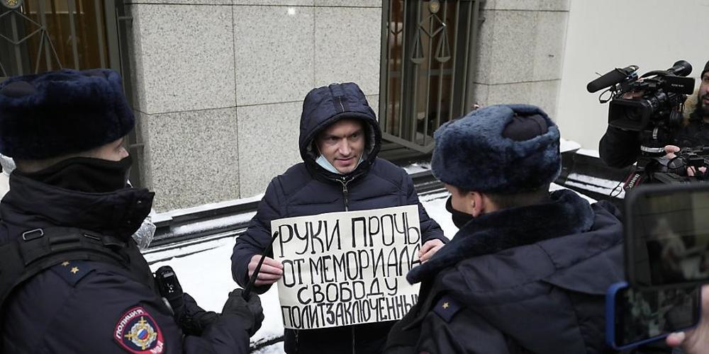 Polizeibeamte halten einen Demonstranten fest, der vor dem Obersten Gerichtshof der Russischen Föderation ein Plakat mit der Aufschrift "Hände weg von Memorial, Freiheit für politische Gefangene" hält. Foto: Pavel Golovkin/AP/dpa