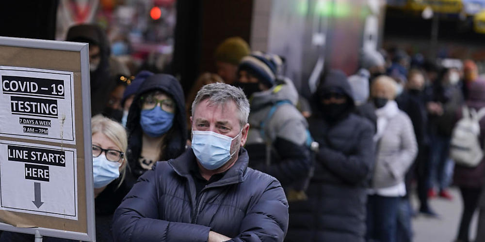Menschen warten in einer Schlange vor einem Covid-Testzentrum am New Yorker Times Square. Foto: Seth Wenig/AP/dpa