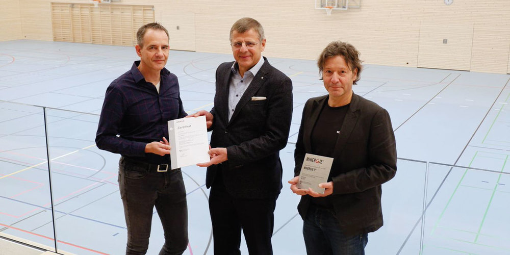 Labelübergabe Minergie-P für eine hocheffiziente Sporthalle:  Walter Vogel (v. l.), Leiter Zertifizierungsstelle Minergie GR beim Amt für Energie und Verkehr Graubünden; Gemeindepräsident Sepp Föhn und Architekt Peter Walser, Gredig Walser Architekten AG. Foto: zVg