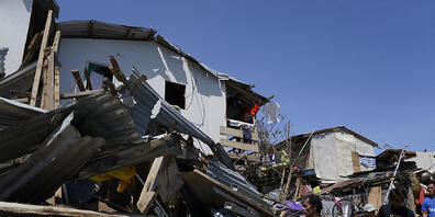 Bewohner suchen nach Habseligkeiten in den Trümmern von zerstörten Häusern. Der Tropensturm «Rai» traf am Donnerstagnachmittag (Ortszeit) mit heftigen Winden und starken Regenfällen auf die Philippinen. Nach Angaben des nationalen Katastrophenschu...