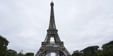 ARCHIV - Menschen sitzen im Champ-de-Mars-Garten vor dem Eiffelturm in Paris. Foto: Michel Euler/AP/dpa