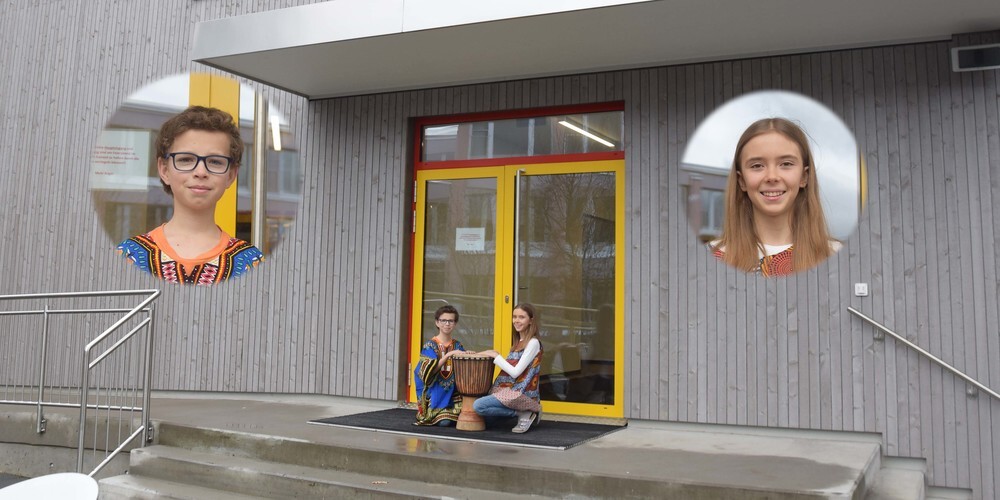 Matthew Edelman und Mariel Kortenbusch in traditionell afrikanischer Kleidung vor dem Pavillon der Sek Eins Höfe Riedmatt.