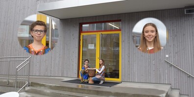 Matthew Edelman und Mariel Kortenbusch in traditionell afrikanischer Kleidung vor dem Pavillon der Sek Eins Höfe Riedmatt.