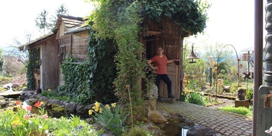 Kathlen Weber in ihrem Garten mit blühenden Pflanzen und Skulpturen aus dem vielfältigen Kunstschaffen.