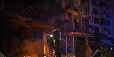 dpatopbilder - Polizisten und Mitglieder der Armee inspizieren das Gebiet nach einer Explosion in Kiew. Foto: Emilio Morenatti/AP/dpa
