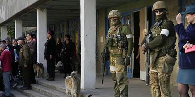 Russische Soldaten bewachen einen Bereich, in dem Zivilisten humanitäre Hilfe, Brot und Wasser erhalten, das vom Ministerium für Notsituationen der «Volksrepublik» Donezk in Mariupol verteilt wird. Foto: Alexander Zemlianichenko/AP/dpa