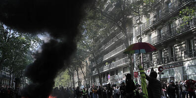 Demonstranten stehen neben brennendem Müll und Materialien, die während eines Demonstrationszuges in Paris zum 1. Mai angezündet wurden. Foto: Lewis Joly/AP/dpa