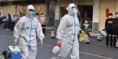 Medizinisches Personal in Schutzkleidung (PSA) geht auf einer Straße, in einem abgeriegelten Bereich. Foto: Sheldon Cooper/SOPA Images via ZUMA Press Wire/dpa