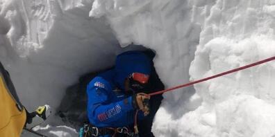 Ein Rettungsspezialist seilt sich zum verunfallten Skifahrer ab. Der Italiener brach durch die Schneedecke, fiel in den darunterliegenden Gletscherbach und wurde unter dem Schnee mehrere Meter talwärts gespült.