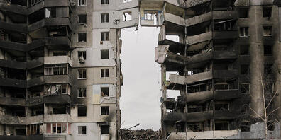 Frauen gehen an einem zerstörten Wohnhaus im ukrainischen Borodjanka vorbei. Foto: Vadim Ghirda/AP/dpa