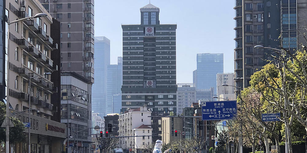 dpatopbilder - Ein Mann in einem Schutzanzug steht auf einer fast menschenleeren Straße in einem abgesperrten Gebiet im Westen von Shanghai. Foto: Chen Si/AP/dpa
