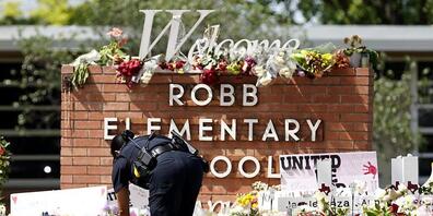 Ein Polizeibeamter legt Blumen vor der Robb Elementary School in der Stadt Uvalde, Texas, USA, nieder. Foto: Wu Xiaoling/XinHua/dpa