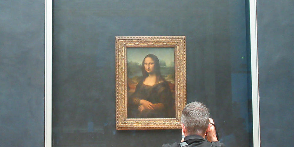 ARCHIV - Ein Besucher fotografiert die "Mona Lisa", die durch Panzerglas geschützt ist. Foto: Sabine Glaubitz/dpa